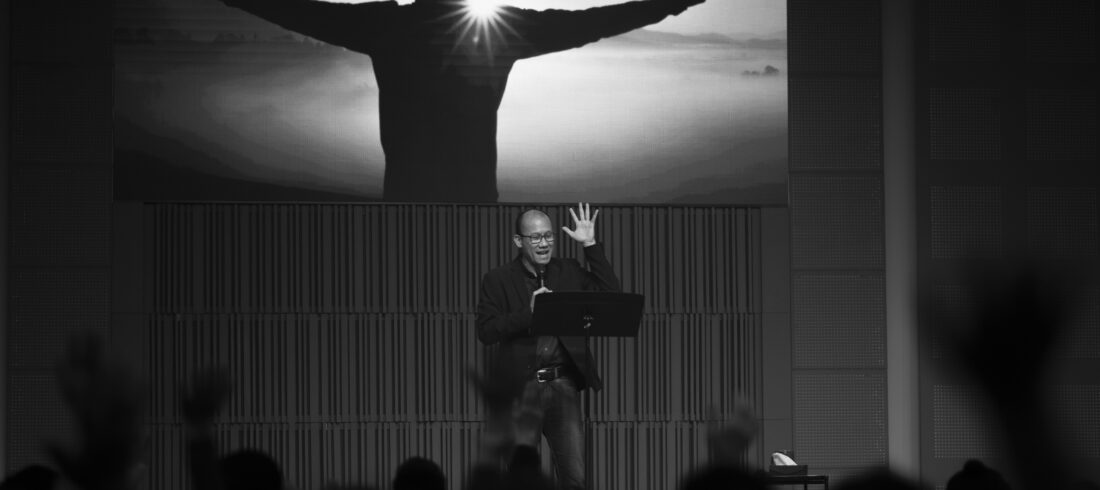 Senior pastor preaching to a congregation with hands raised in worship, highlighting the spiritual and emotional weight leaders carry in church communities.