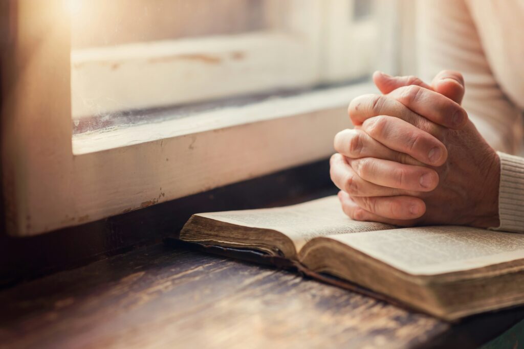 A job seeker praying before an interview with a resume and portfolio, reflecting faith, confidence, and preparation.